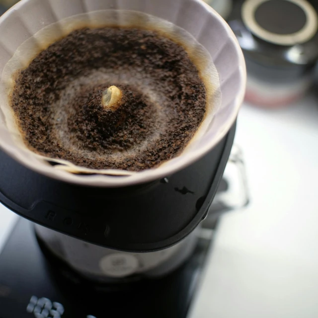 a black coffee pot filled with liquid on top of a stove