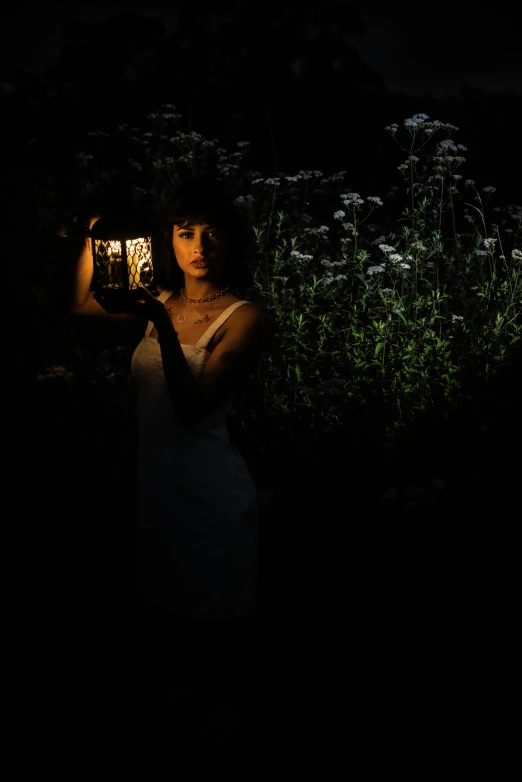 a woman in the dark holding a lit up cell phone