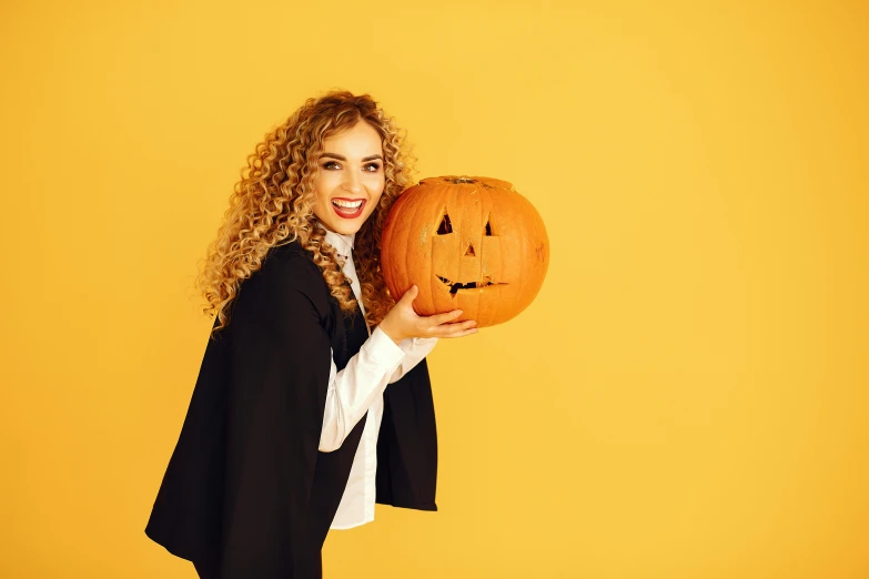 a woman holding up a pumpkin with a smiling face on it