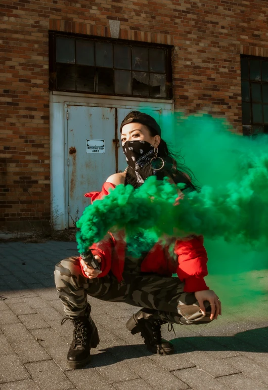 a woman with green hair wearing gas mask, holding soing while crouching down