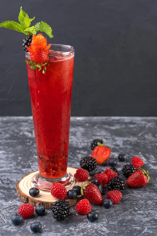 a tall glass filled with some red liquid and berries