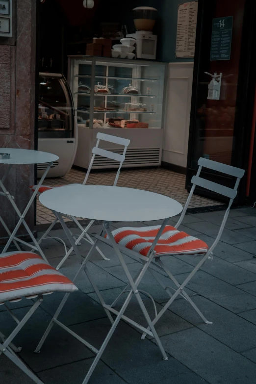 three white folding chairs with an orange seat