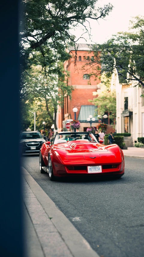 red sports car drives down the street near other cars