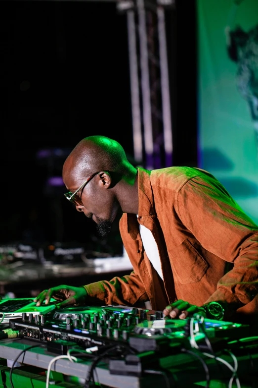 a man in glasses and a brown jacket at a dj set