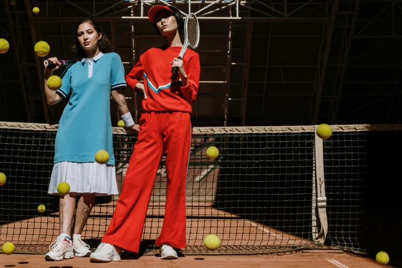 two women in tennis uniforms are posing by a net