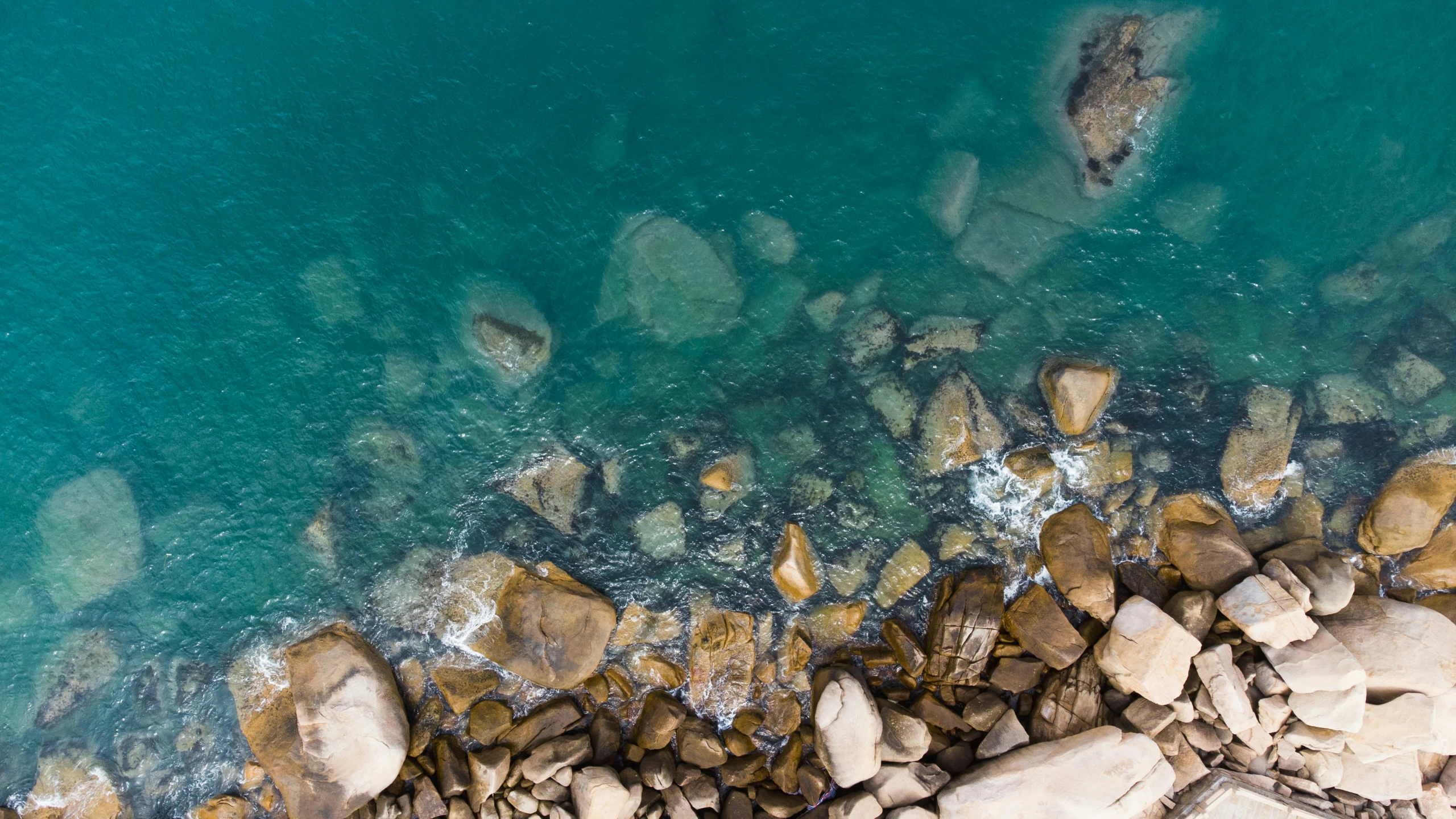 an aerial view of some rocks and blue water