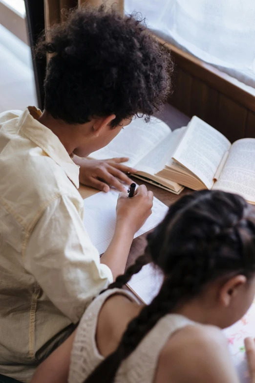 two girls sit at a table with books in front of them