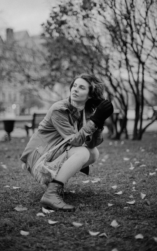 a woman in a park squatting on the ground