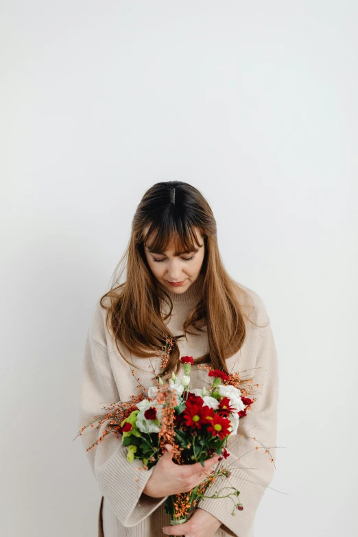 a woman holding flowers and looking down at it