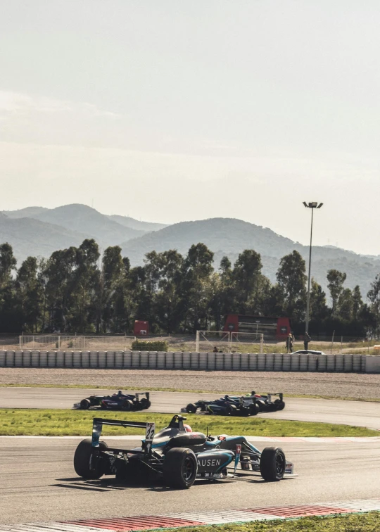 race cars driving on a track with mountains in the background