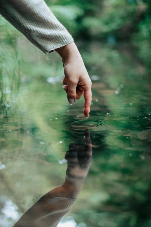 a person reaches for the water with a hand