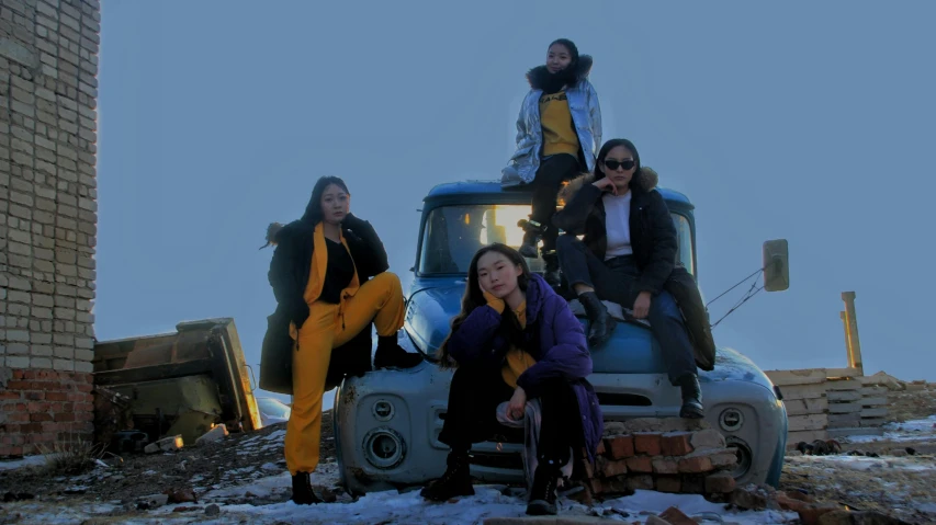 four people posing for a po on a truck