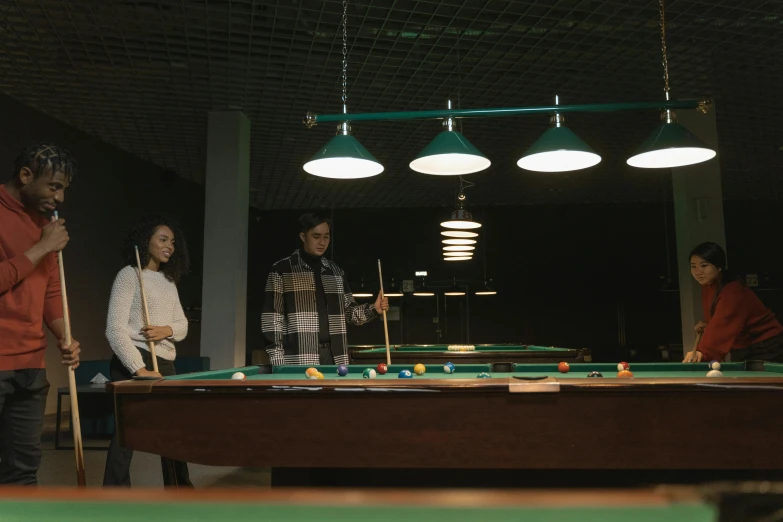 four people are playing pool and ping pong