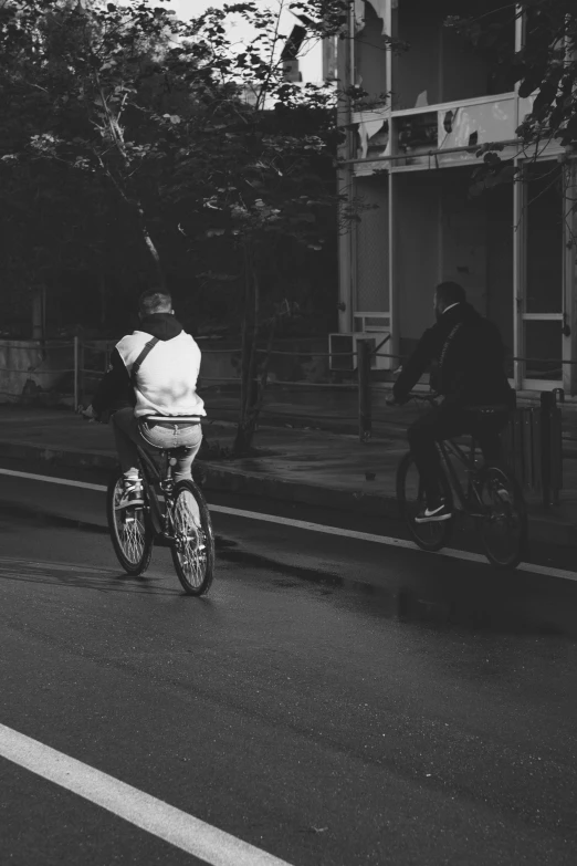 black and white image of person on bicycle riding down the road