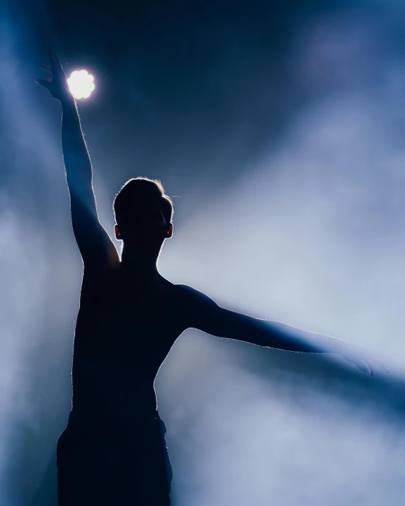 a person standing at the end of a stage with their arms raised in the air