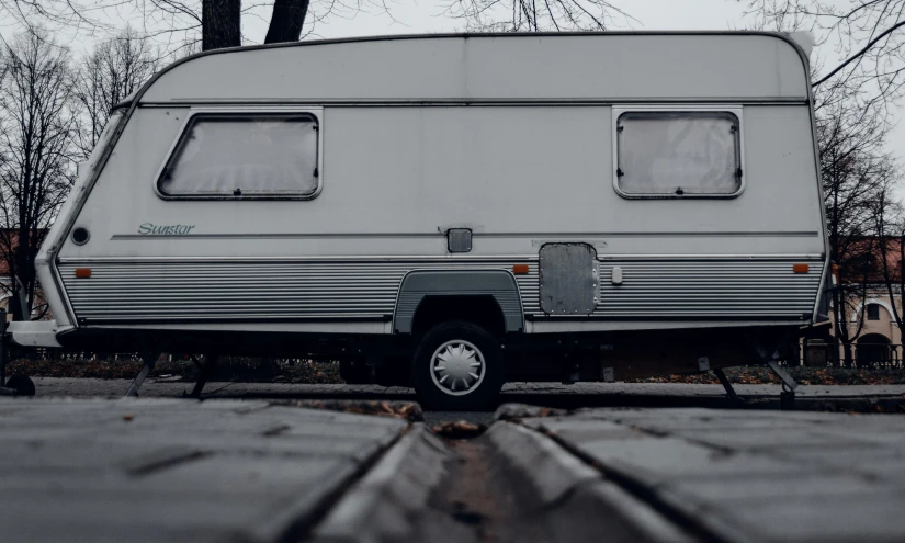 a rv parked next to a tree on the side of the road