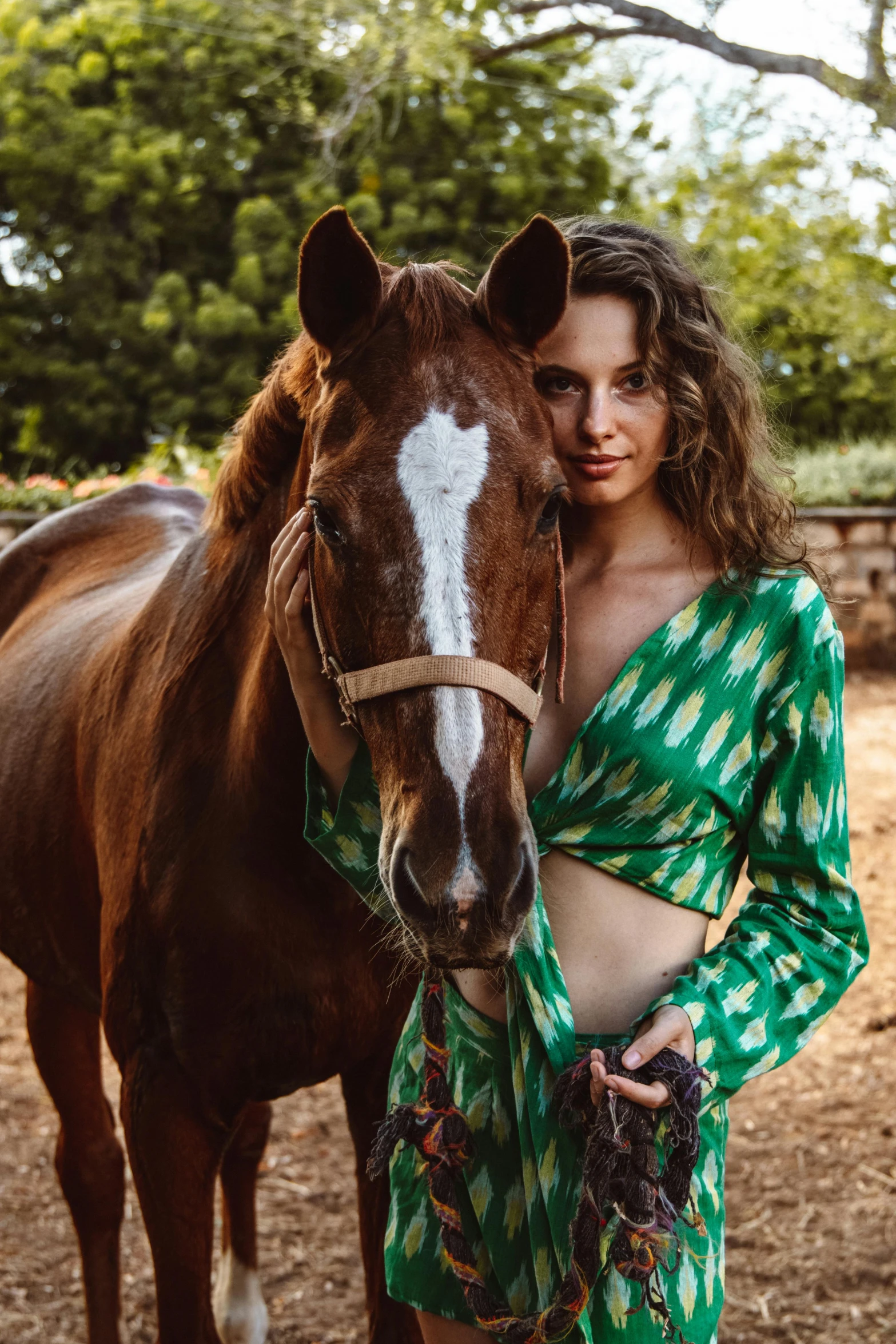 a woman in green dress standing next to a brown horse