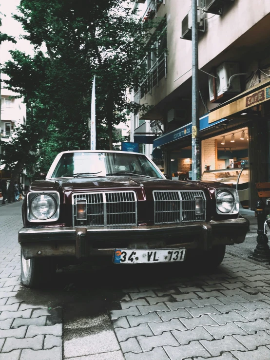 a red vintage car is parked near a building