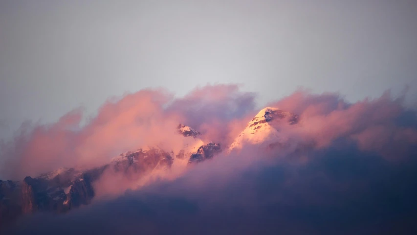 a group of mountains shroud with pink and orange smoke