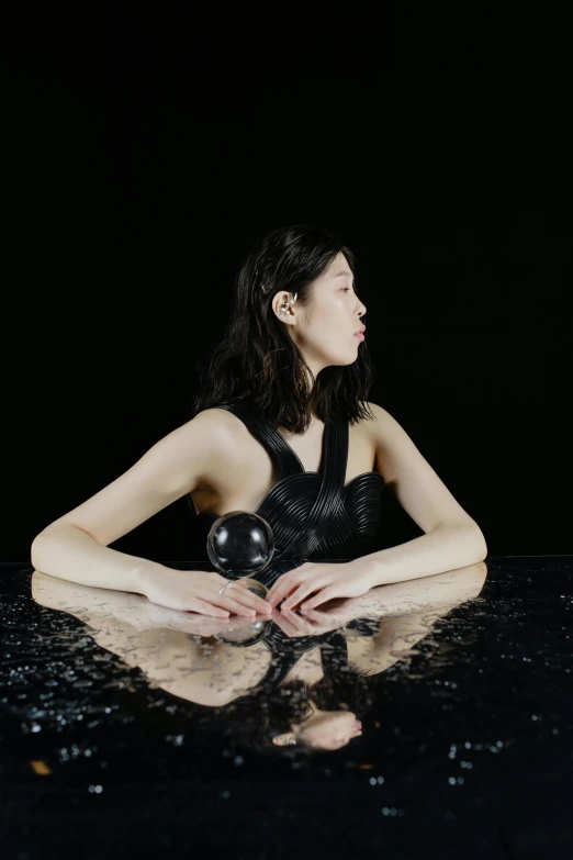 woman in black dress sitting on the ground with her legs crossed