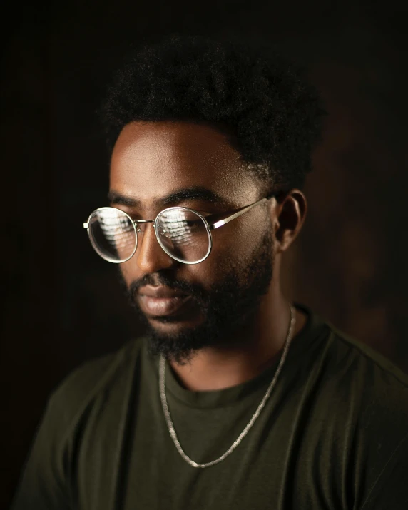 a young man wearing round glasses looking off into the distance