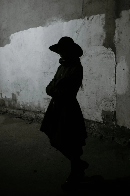 a woman standing in the dark near a wall