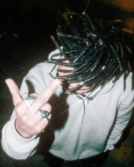a person wearing dreadlocks making the v sign