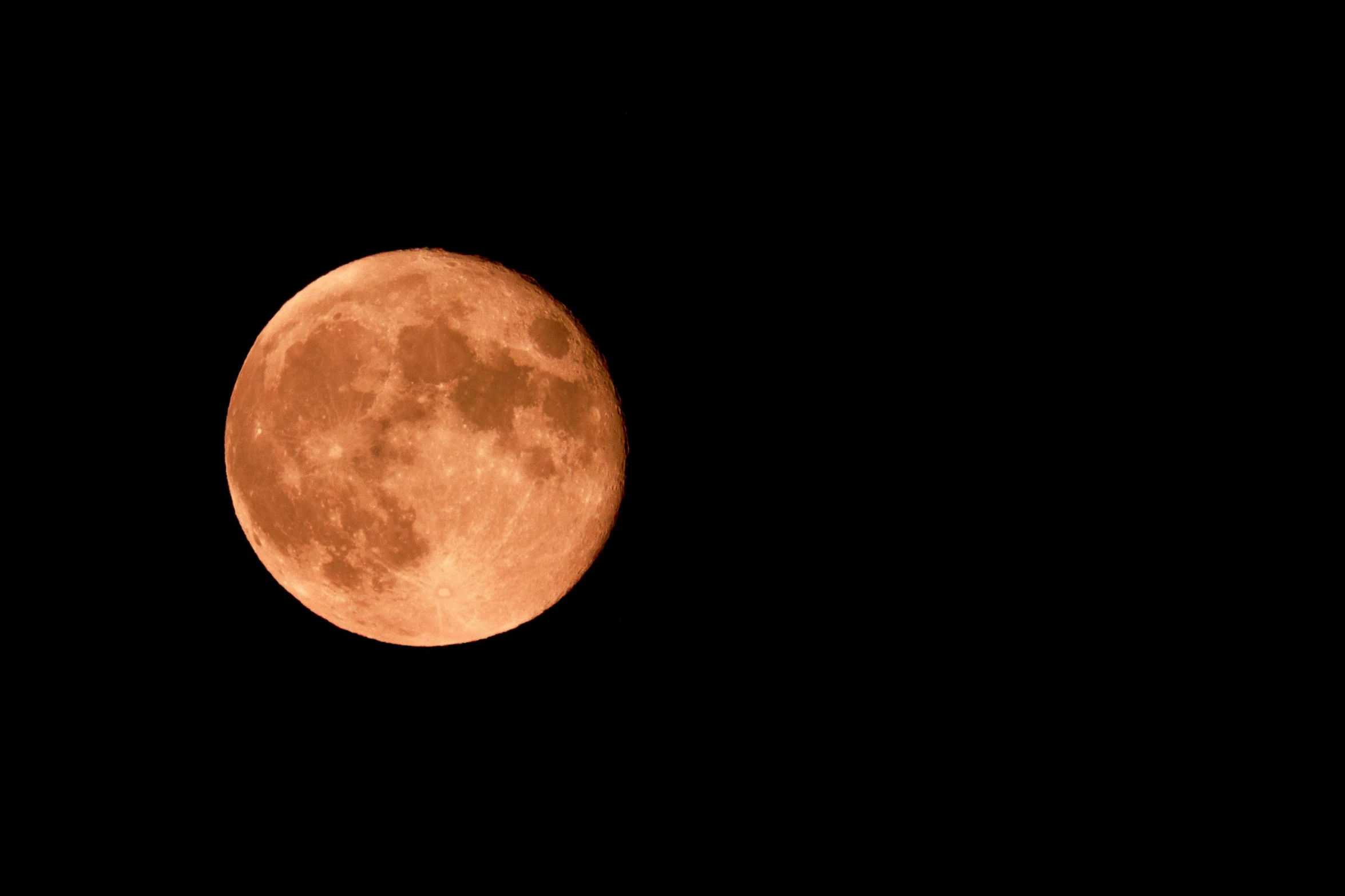 a view of a bright red full moon, the right half visible