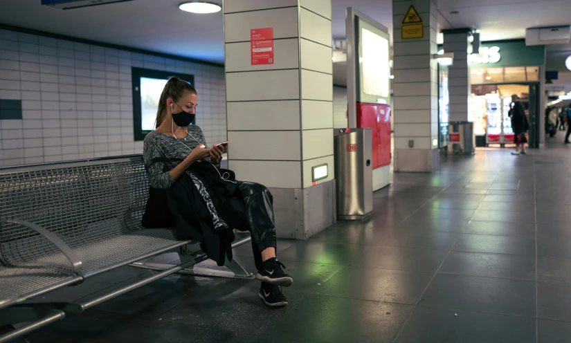 a person sitting in the airport while checking their cell phone