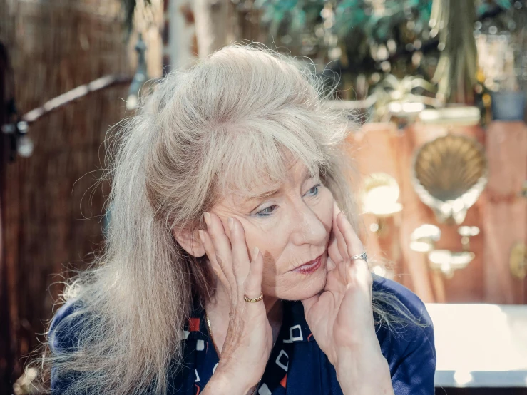 an older woman with long blonde hair sitting at a table