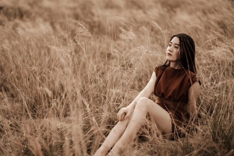 woman sitting in a field of brown grass