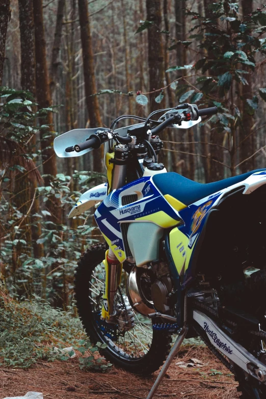 a blue and yellow motorcycle parked in the woods