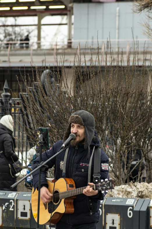 the man is playing his guitar outside and singing