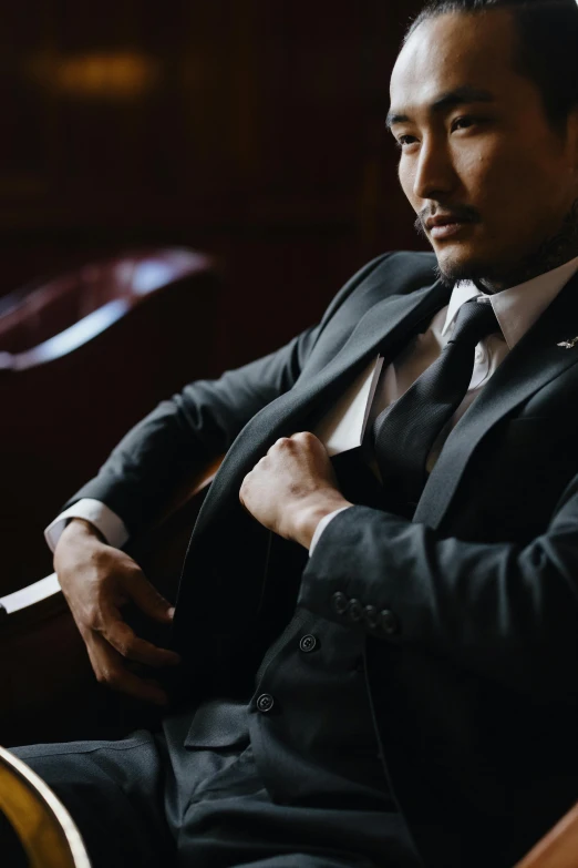 a man in a suit and tie sitting next to a bench