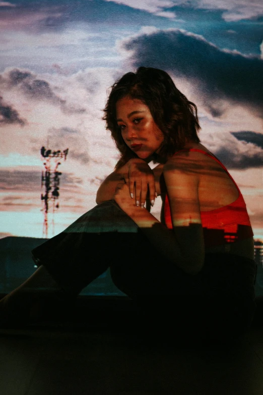 woman sitting by water with a sky background