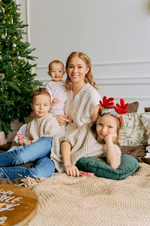 two mothers and their children sitting on a christmas tree with a christmas card attached