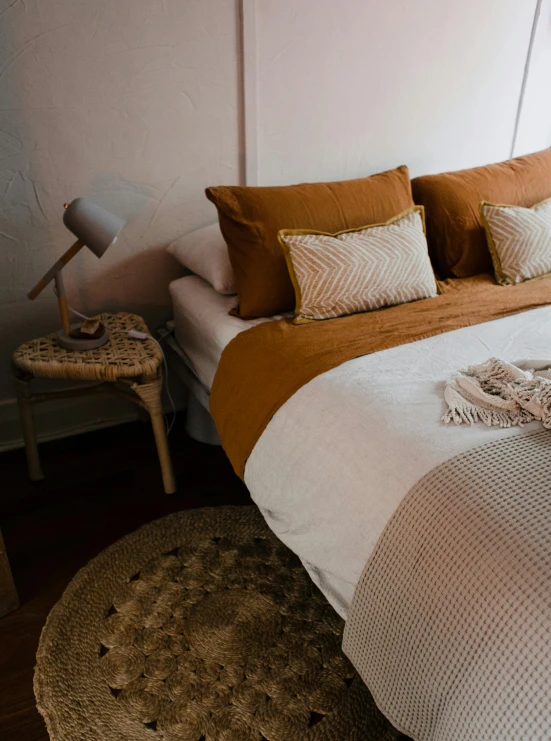 a bed with white sheets, brown and beige pillows