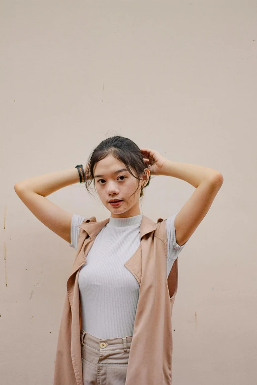 a woman holds her hair in the air while leaning against a wall