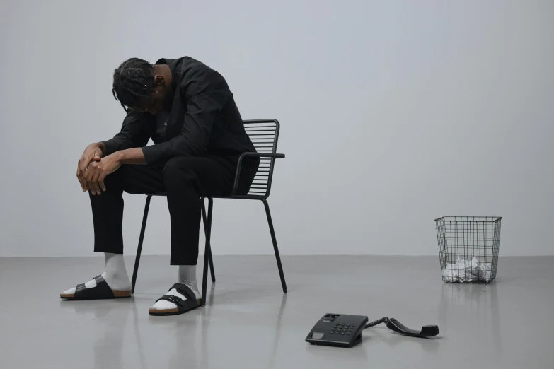 a man sits on a chair and covers his face with his hands