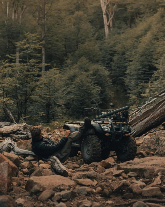 a person is sitting on rocks near a trail