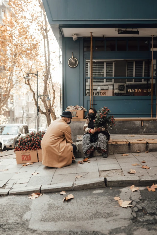 two people sitting on the sidewalk and on the sidewalk