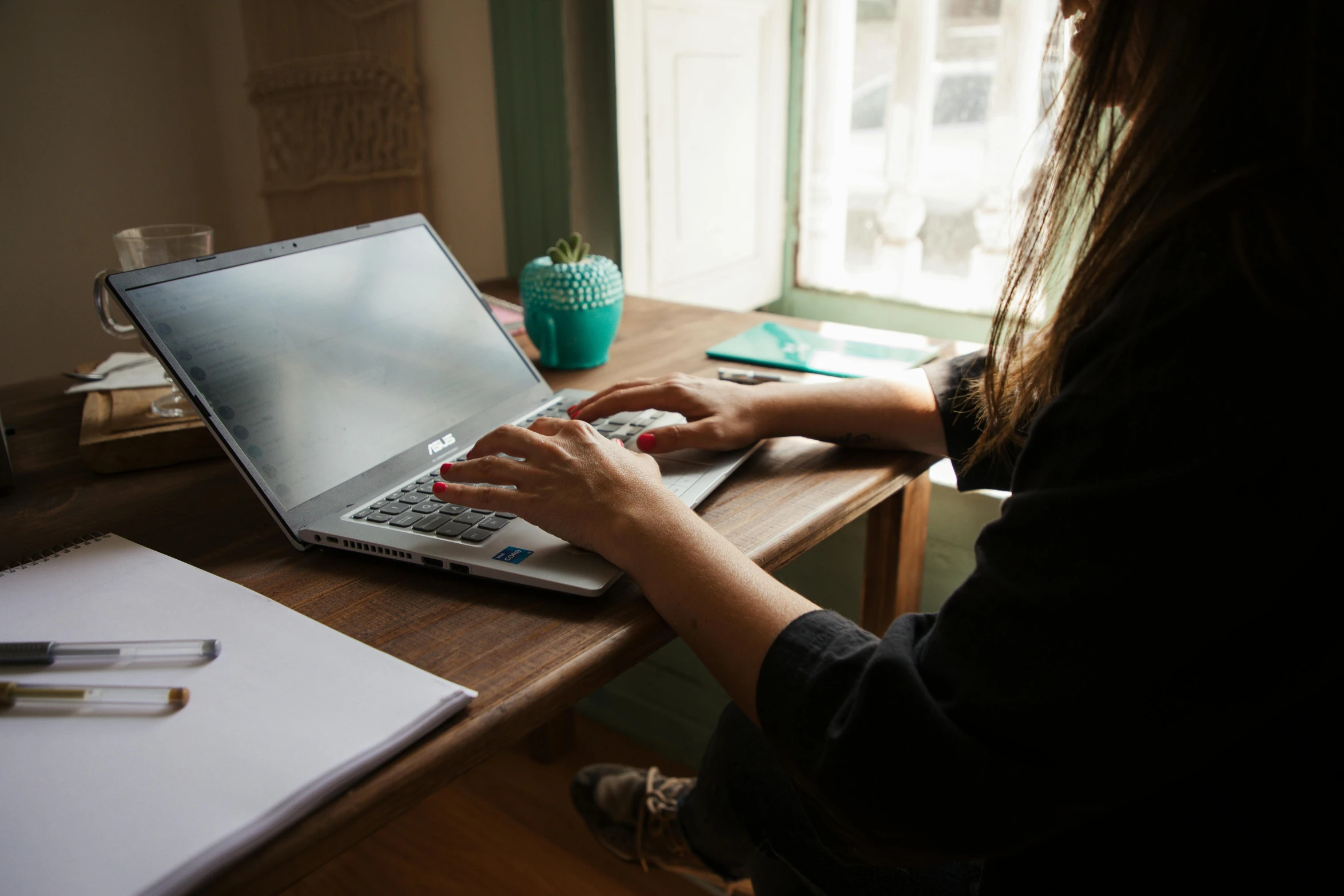 woman sitting in front of her laptop looking out the window