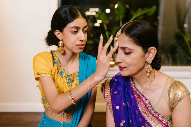 two women dressed in traditional indian clothes and are touching each other's hands