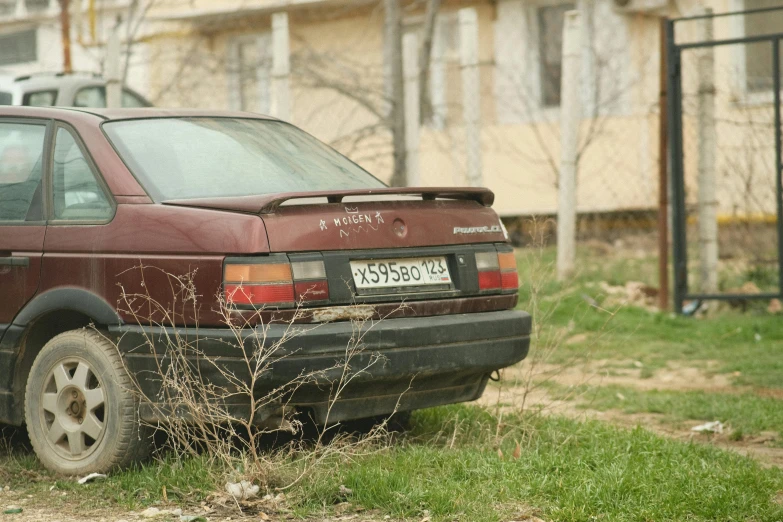 an old car parked in the grass on a street