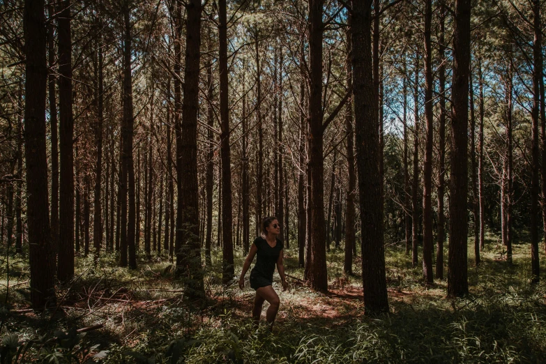 a woman stands in front of the trees on a path