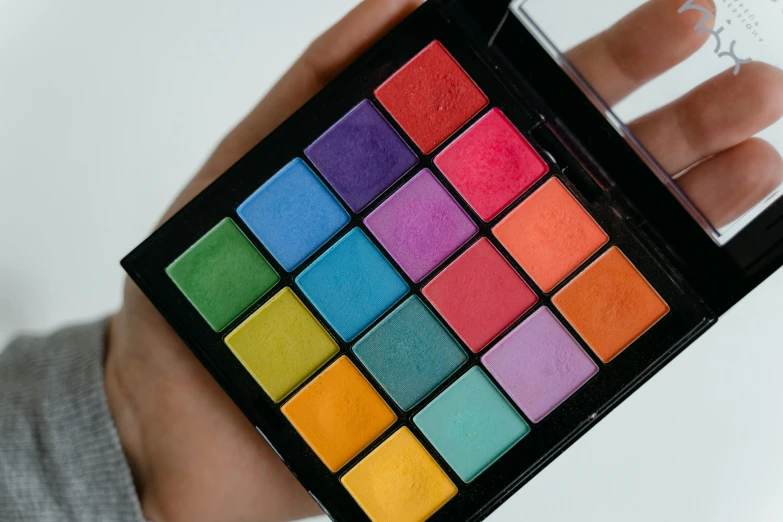 the person holds a bright colored makeup palette