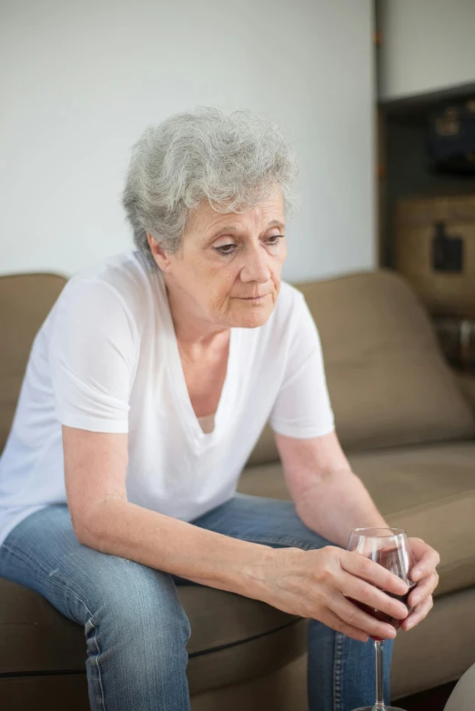 a woman sitting on the couch looking at her glass