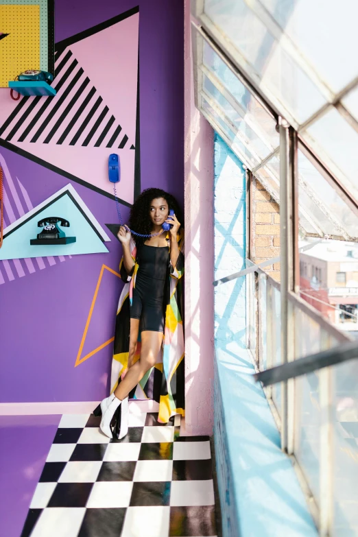 a woman is talking on a cell phone in front of purple and black art