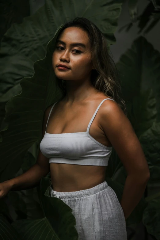 a woman standing between a large leafy plant