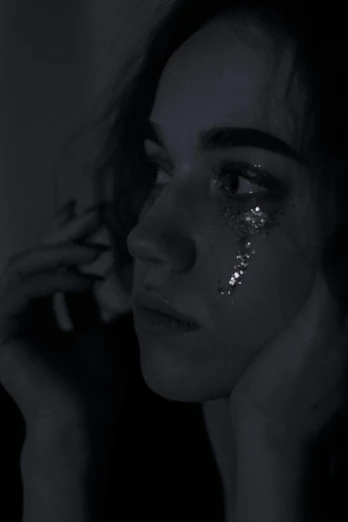 a woman standing in the dark with sparkle on her face